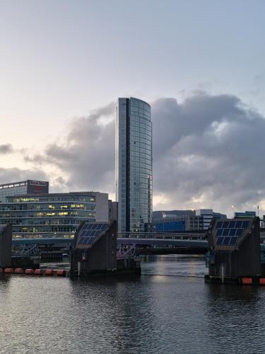 a bridge over a river with a tall building at Sky High Ensuite Bedroom in Shared Apartment in Belfast City Centre in Belfast