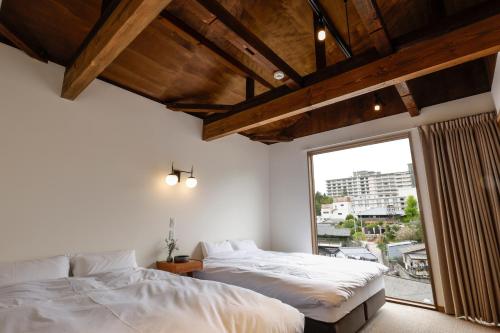 a bedroom with two beds and a large window at 貸別荘 楓-Fū- 有馬 in Arima