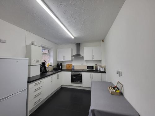 uma cozinha com armários brancos e uma mesa em Fern House - free off road parking included em Buxton