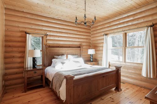 ein Schlafzimmer mit einem Bett in einem Blockhaus in der Unterkunft Fiddler Lake Resort Chalet 47 Deer in Mille-Isles