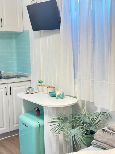a kitchen with a table and a blue suitcase at Tiny Amor in Berkeley Vale