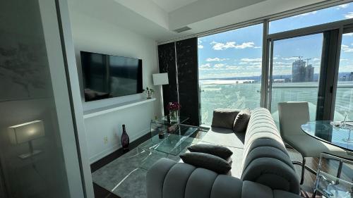 ein Wohnzimmer mit Couch und großem Fenster in der Unterkunft DOWNTOWN, LUXURY CONDO, CN TOWER, ROGERS CENTER, SCOCIA ARENA, UNOBSTRUCTED VIEW in Toronto