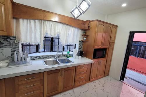 eine Küche mit Holzschränken, einem Waschbecken und einem Fenster in der Unterkunft Adorable Arouca 1BDR Apartment in Arouca