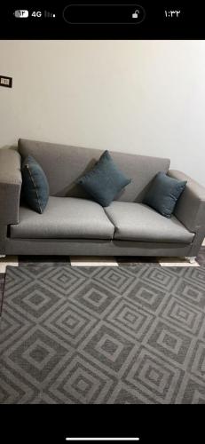 a gray couch with blue pillows in a living room at شقة الزقازيق in Manshīyat as Sādāt