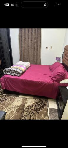 a bed in a room with a purple bedspread at شقة الزقازيق in Manshīyat as Sādāt