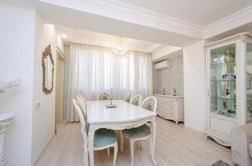 un comedor blanco con mesa y sillas en 5A beautiful apartment in the center of the capital photo original, en Ereván