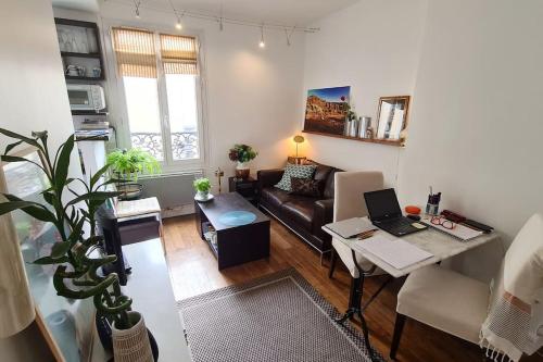 un salon avec un canapé et une table avec un ordinateur portable dans l'établissement Logement entier proche de Butte aux cailles, à Paris