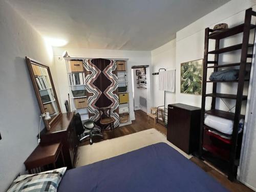 - une chambre avec un lit, un bureau et des étagères dans l'établissement Logement entier proche de Butte aux cailles, à Paris