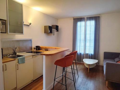 eine Küche mit einer Theke und Stühlen in einem Zimmer in der Unterkunft Cocon urbain aux portes de Paris/parc Montsouris in Montrouge