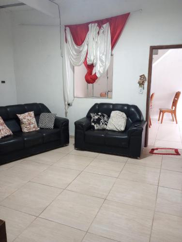una sala de estar con 2 sofás negros y un espejo en Casa temporada 2 quartos, en Serra
