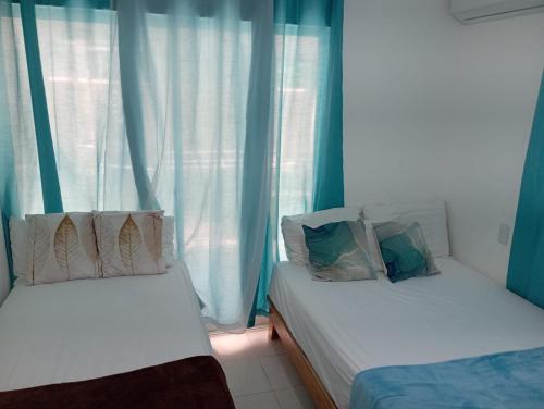 two beds in a room with blue curtains at Hostal Palmas De Punta Cana in Punta Cana