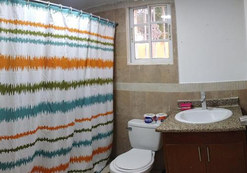 a bathroom with a toilet and a shower curtain at Hostal Palmas De Punta Cana in Punta Cana