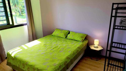 1 dormitorio con 1 cama con edredón verde en MOOREA - Oceanie Lodge, en Pihaena