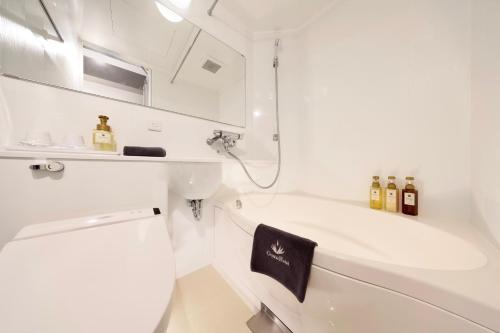 a white bathroom with a sink and a bath tub at Doutonbori Crystal Hotel Ⅱ in Osaka