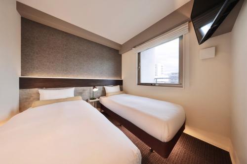 two beds in a small room with a window at Doutonbori Crystal Hotel Ⅱ in Osaka