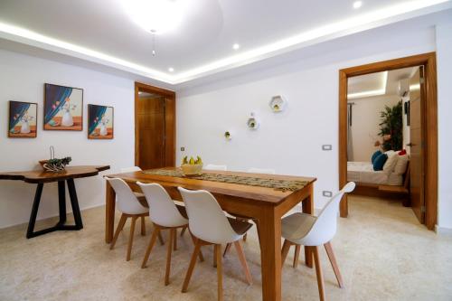 a dining room with a wooden table and white chairs at Villa loren A3 in Las Terrenas