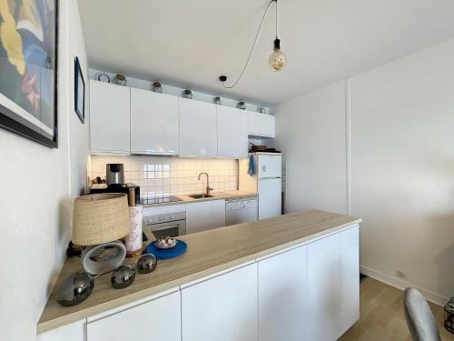 une cuisine avec des armoires blanches et un comptoir dans l'établissement Appartement en bord de mer avec terrasse et parking - FR-1-361-85, à Jullouville