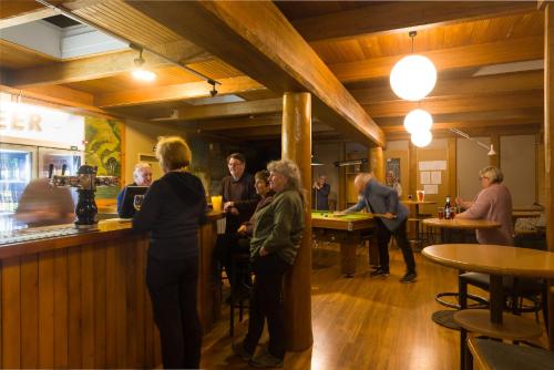 a group of people standing at a bar in a restaurant at Last Resort Karamea in Karamea