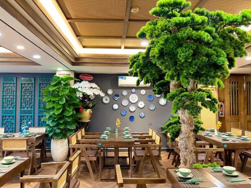a restaurant with wooden tables and a large tree at Happy Life Green Hotel in Ho Chi Minh City