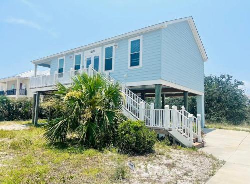 a house on the beach with a palm tree in front at Beautiful Pensacola beach house in Pensacola Beach