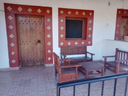Habitación con sillas, TV y puerta. en Hotel Cabañas Chalamu, en Pátzcuaro