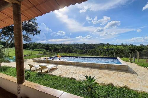 una gran piscina con 2 bancos en Chácara Urbana Quiosque Canto do Curió en Araxá