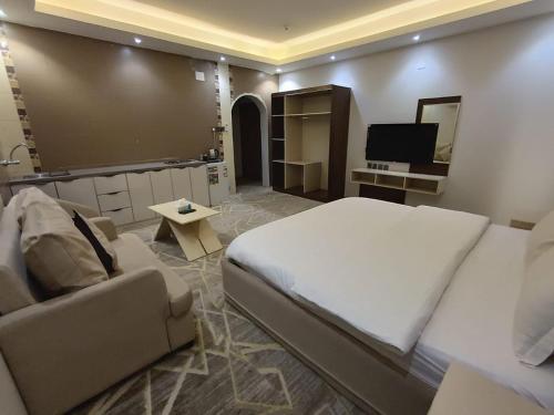 um quarto com uma cama, um sofá e uma televisão em Maro Hotel em Abha