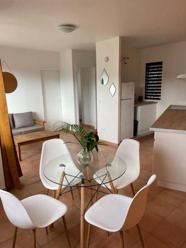 - un salon avec une table en verre et des chaises blanches dans l'établissement Prestige, à Fort-de-France
