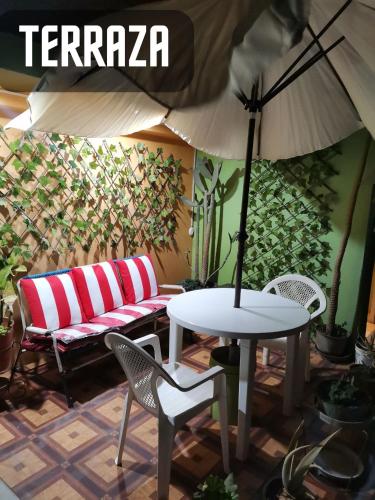 a patio with a table and a bench and an umbrella at Sombrero de Paja in Chiclayo