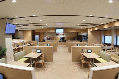 a restaurant with tables and chairs and televisions at Castle Inn Toyokawa in Toyokawa