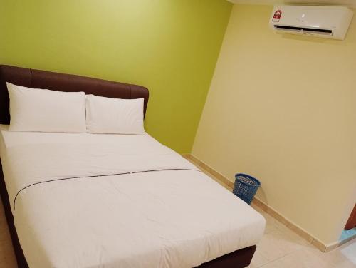 a bedroom with a bed with white sheets and a green wall at HOTEL SAHARA INN TANJUNG MALIM in Kampong Chabang