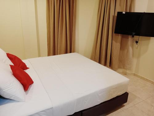 un letto bianco con cuscini rossi in una stanza di HOTEL SAHARA INN TANJUNG MALIM a Kampong Chabang