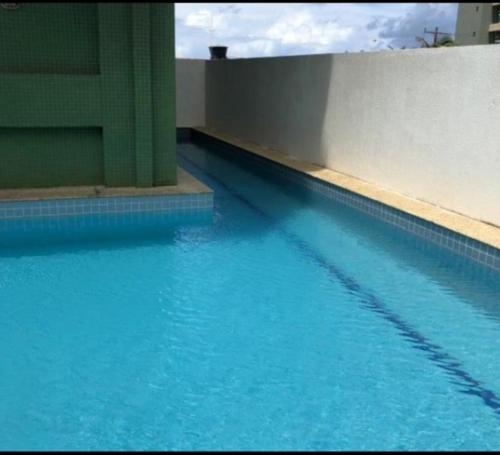 a large pool of blue water next to a building at Loft Praia de Armação in Salvador