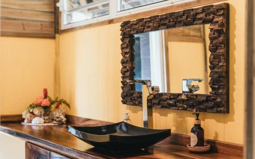 uma casa de banho com um lavatório preto e um espelho em Bungalow Bali Hai em Fare