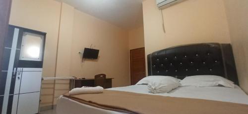 a bedroom with a bed with a black headboard and white pillows at Graha Aditya Syariah in Palembang