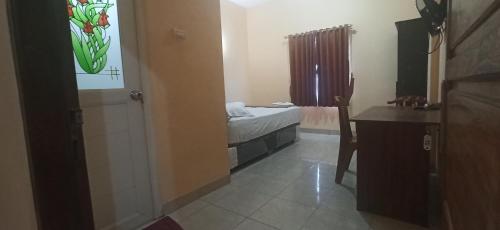 um pequeno quarto com uma cama, uma secretária e uma janela em Graha Aditya Syariah em Palimbão