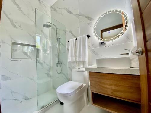 a bathroom with a shower and a toilet and a sink at Elegante Apartamento A 100 mts la playa de los Minos RSJ in Río San Juan