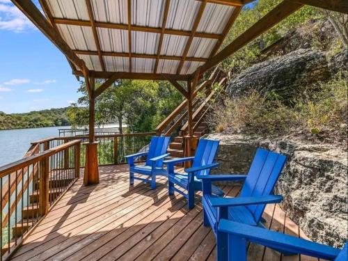 four blue chairs sitting on a deck next to the water at A Rare Find! - Bright & Gorgeous Lake Home in Marble Falls in Marble Falls