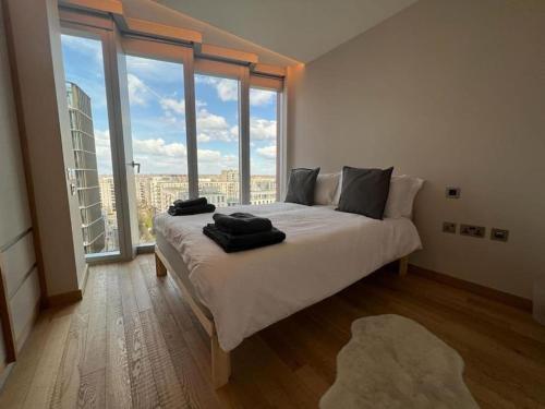 a bedroom with a large bed and large windows at NEW Manhattan Loft Gardens Stratford in London