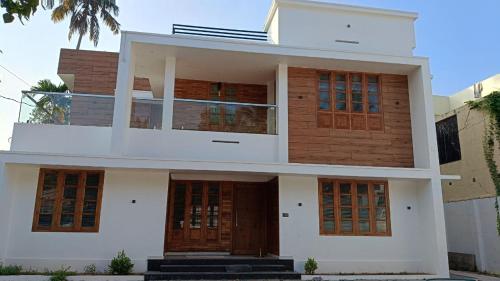 a large white house with brown doors and windows at Tranquil Home in Trivandrum