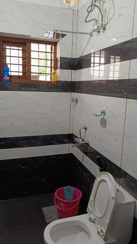 a bathroom with a toilet and a red bucket at Tranquil Home in Trivandrum
