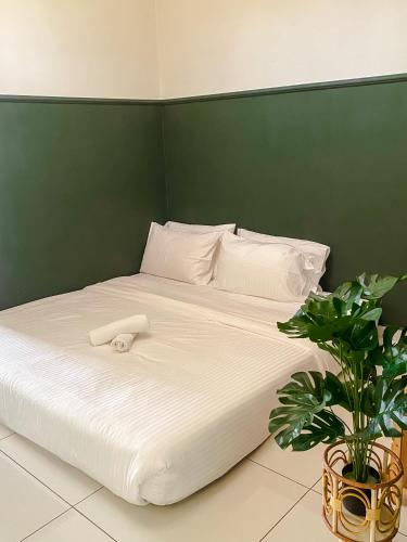 a large white bed with a green wall at 5BR5B in Skudai, 15mins to UTM&Sutera, 7-16pax, WiFi in Skudai
