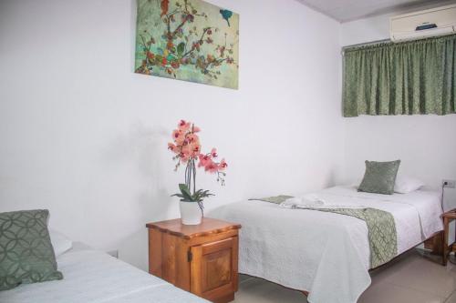 Zimmer mit 2 Betten und einer Blumenvase auf dem Tisch in der Unterkunft Hotel Golfito in Golfito