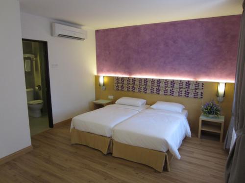a bedroom with two beds and a purple wall at Bella Vista Waterfront Resort, Kuah Langkawi in Kuah