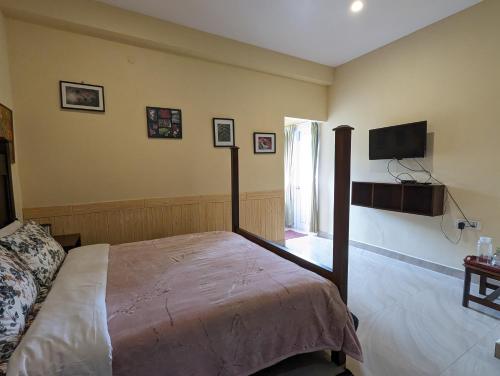 1 dormitorio con 1 cama y TV de pantalla plana en Cloudwalks Homestay en Kodaikānāl