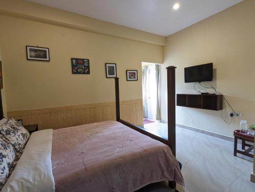 1 dormitorio con 1 cama y TV de pantalla plana en Cloudwalks Homestay en Kodaikānāl