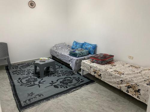 a room with two beds and a table on a rug at Barbarous in Ajim