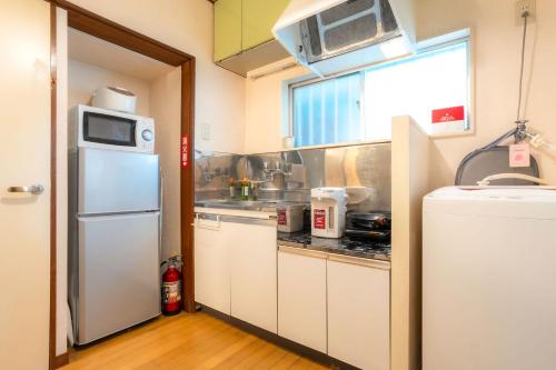 a small kitchen with a refrigerator and a sink at Budget 3-Bedrooms Villa#4mins to Ikebukuro#Hight speed wifi#Near Train Tracks in Tokyo