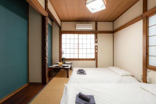 two beds in a room with a table and a window at 五十岚民宿 地铁站步行4分 免费高速 WI-FI TraditionCozy Japanese Villa in Ikebukuro 6mins St with Hight speed WIFI in Tokyo