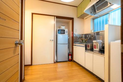 a kitchen with a white refrigerator in a room at 五十岚民宿 地铁站步行4分 免费高速 WI-FI TraditionCozy Japanese Villa in Ikebukuro 6mins St with Hight speed WIFI in Tokyo